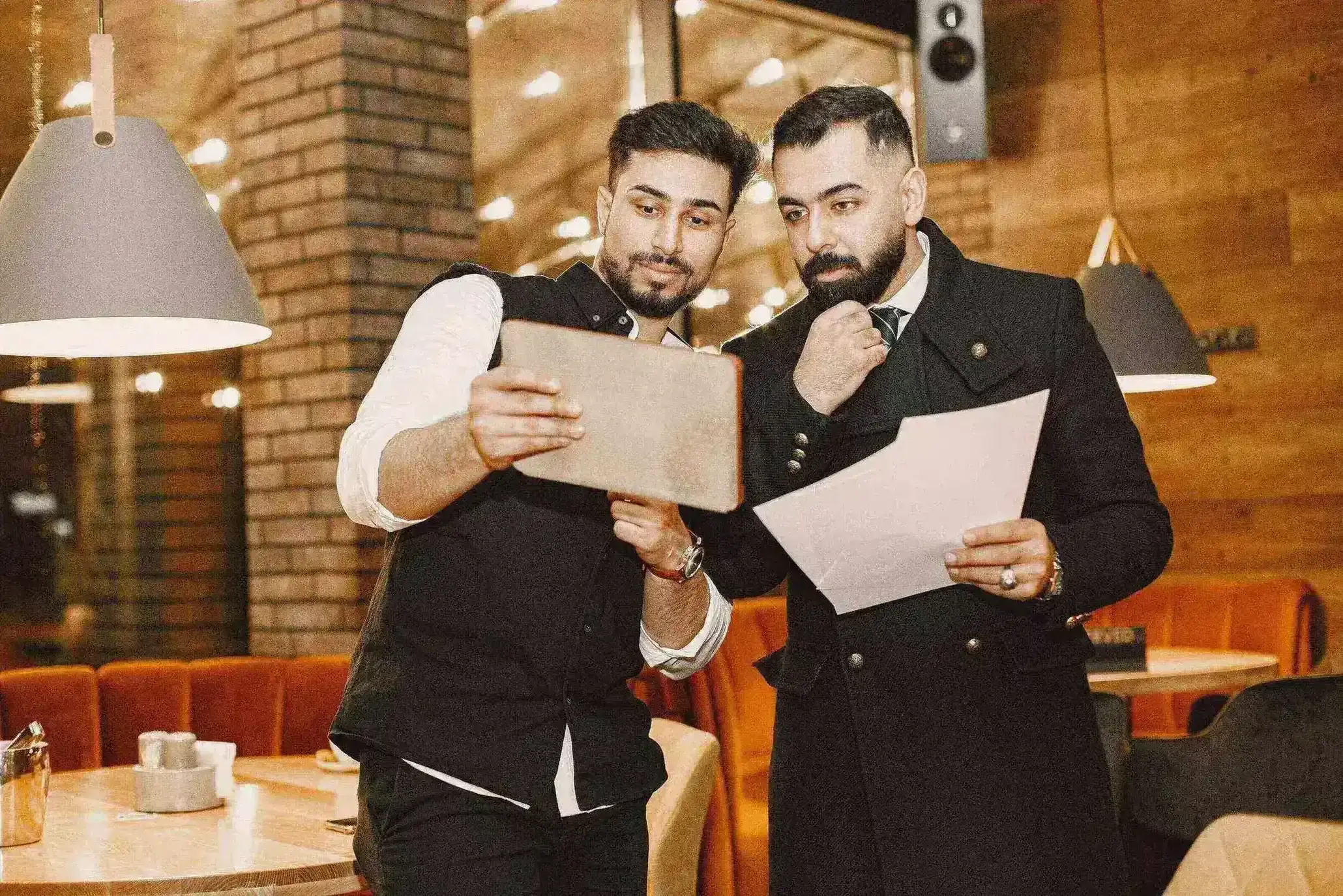 Deux personnes examinent des documents et une tablette pour préparer l’organisation d’un restaurant.